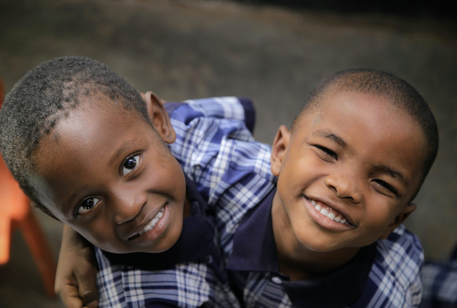 Two happy Ugandan boys in school uniforms smiling at Kabubbu Community Primary School, supported by Kabubbu Development Project.